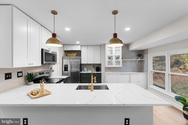 kitchen featuring sink, pendant lighting, decorative backsplash, white cabinets, and appliances with stainless steel finishes