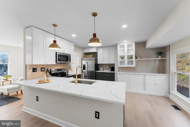 kitchen with appliances with stainless steel finishes, white cabinetry, a wealth of natural light, and sink