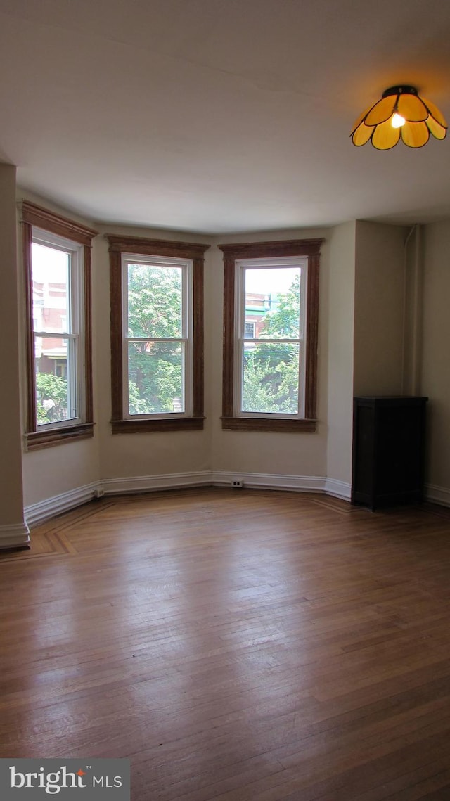 unfurnished room featuring plenty of natural light and hardwood / wood-style floors