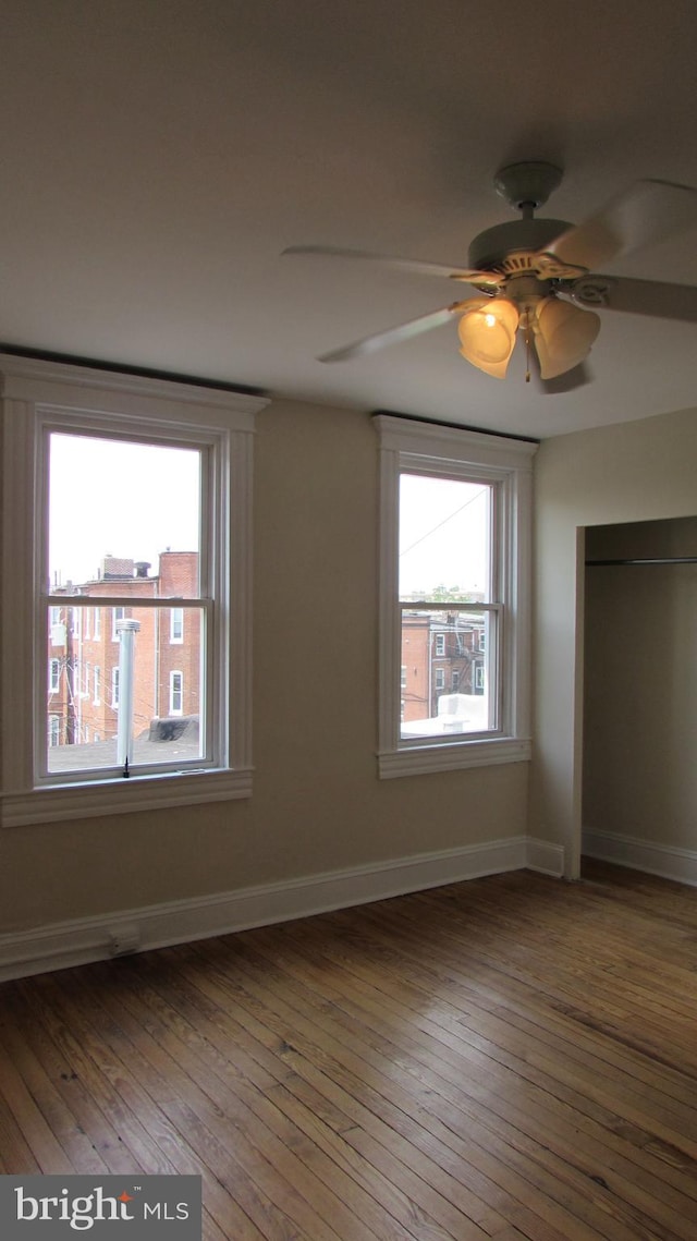 unfurnished bedroom featuring ceiling fan, multiple windows, and wood-type flooring