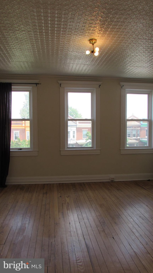 empty room with wood-type flooring and an inviting chandelier