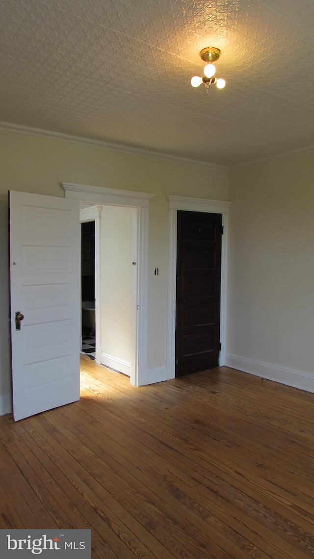 empty room with a textured ceiling, ornamental molding, and hardwood / wood-style floors