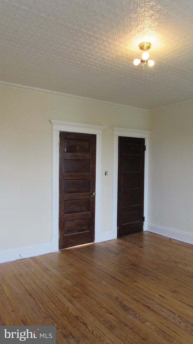 empty room with a textured ceiling, dark hardwood / wood-style floors, and crown molding