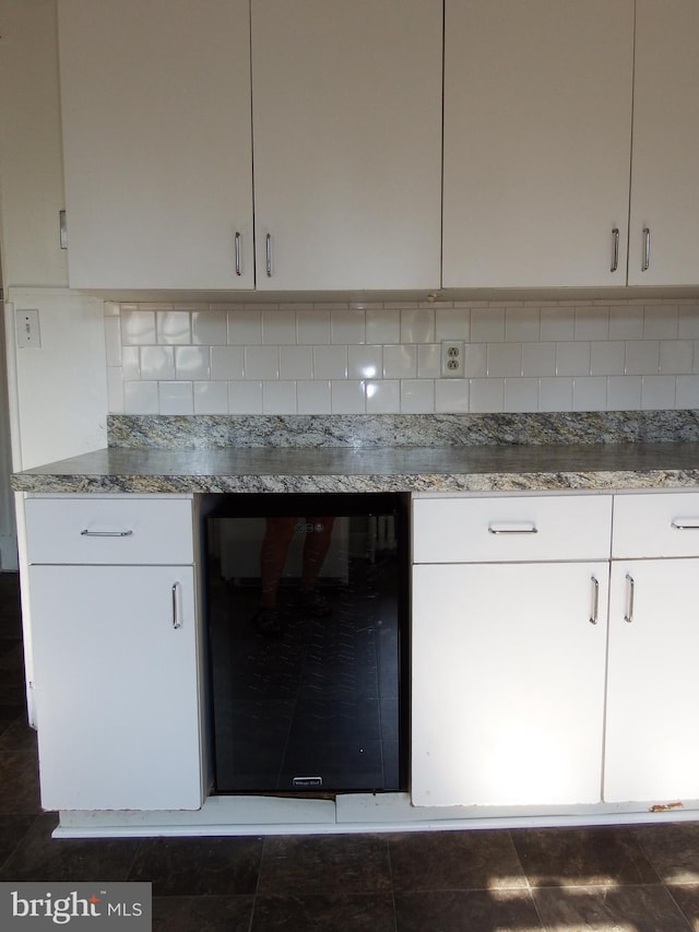 room details with backsplash, white cabinets, and wine cooler