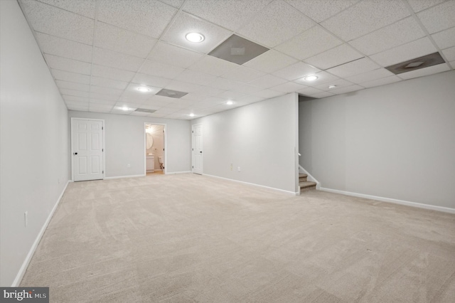 basement featuring a drop ceiling and light carpet