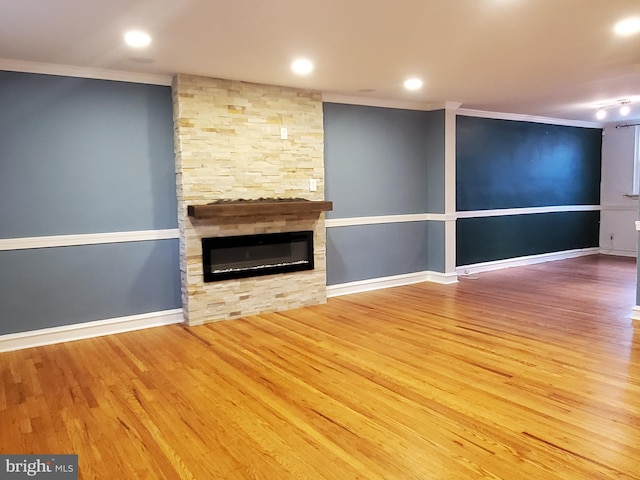 unfurnished living room featuring hardwood / wood-style floors, a stone fireplace, and crown molding