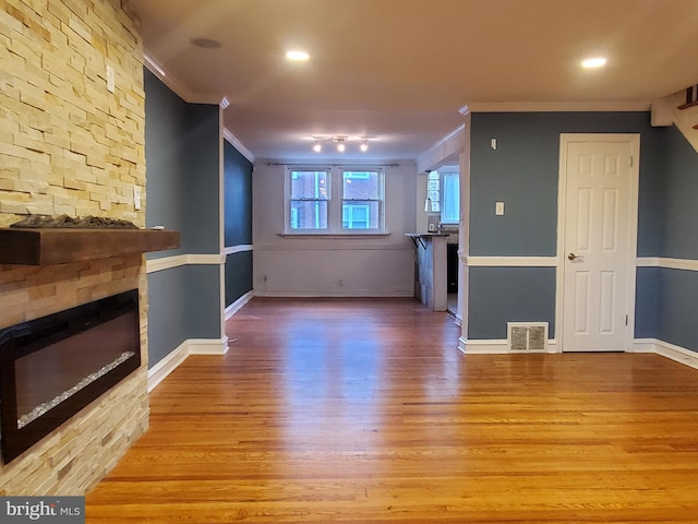 unfurnished living room featuring crown molding, light hardwood / wood-style flooring, and a fireplace