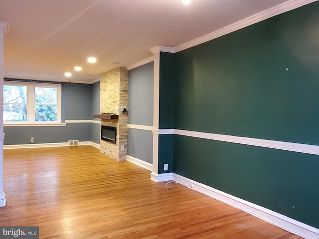 unfurnished living room featuring crown molding, a fireplace, and light wood-type flooring