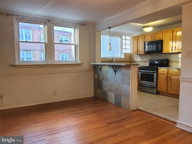 kitchen featuring light hardwood / wood-style floors, tasteful backsplash, stainless steel gas stove, and a wealth of natural light