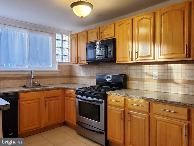 kitchen featuring decorative backsplash, light tile patterned floors, black appliances, stone counters, and sink