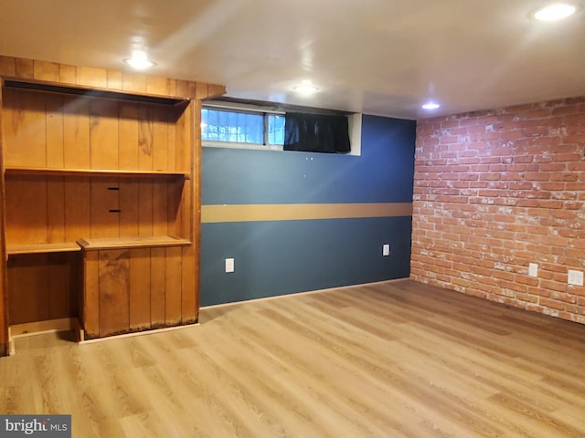 basement featuring hardwood / wood-style flooring and brick wall