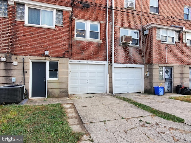 rear view of house with cooling unit, central AC, and a garage