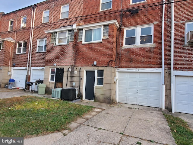 rear view of property featuring a garage, cooling unit, and central AC unit