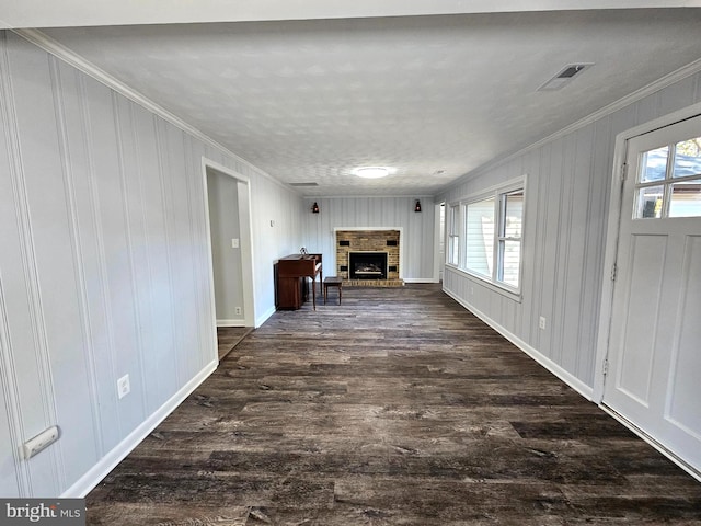 unfurnished living room featuring dark wood-type flooring, a healthy amount of sunlight, a textured ceiling, and ornamental molding