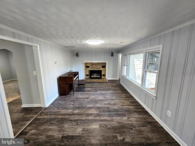 corridor with dark hardwood / wood-style flooring, ornamental molding, and a textured ceiling