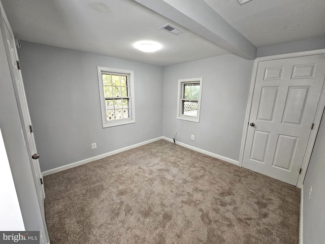 unfurnished bedroom with beam ceiling and carpet floors