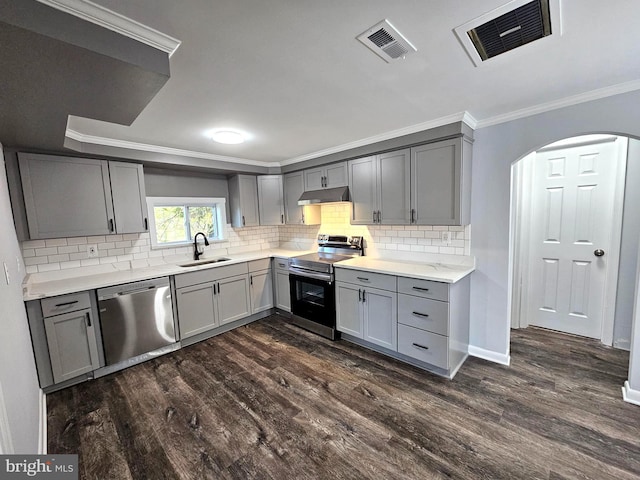 kitchen featuring sink, dark wood-type flooring, crown molding, gray cabinets, and appliances with stainless steel finishes