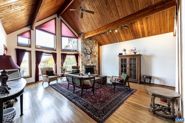 living room with wood ceiling, beam ceiling, a stone fireplace, high vaulted ceiling, and light hardwood / wood-style floors