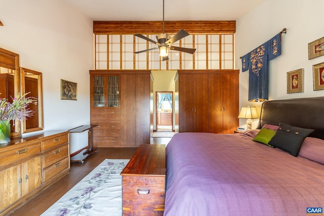 bedroom with ceiling fan, beamed ceiling, a high ceiling, and dark hardwood / wood-style flooring