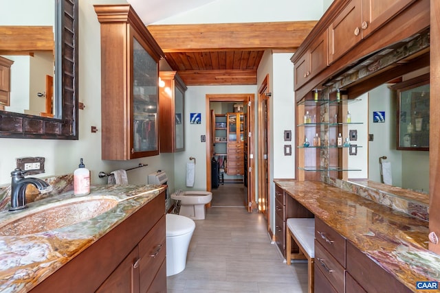 bathroom with toilet, beamed ceiling, a bidet, wooden ceiling, and vanity