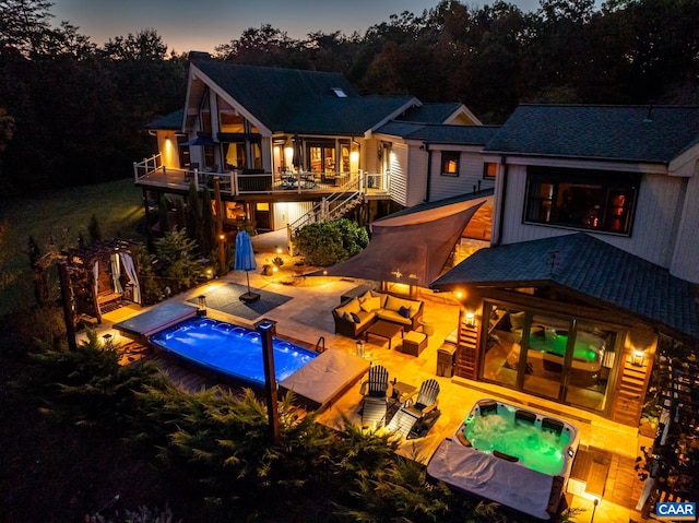 back house at dusk with a patio area and a swimming pool with hot tub