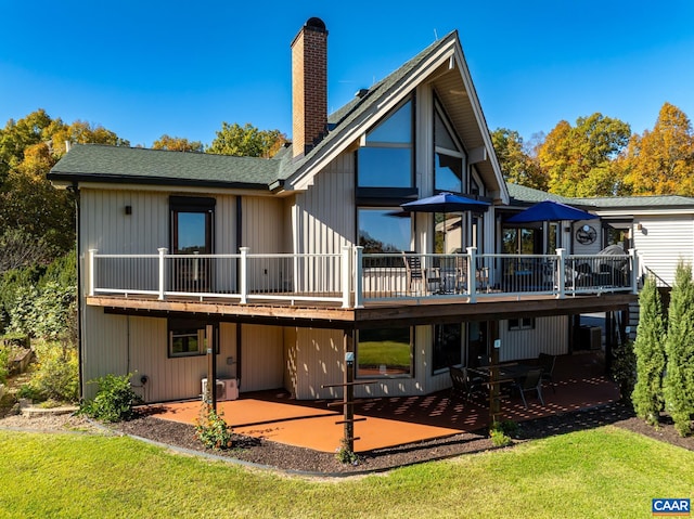 rear view of house featuring a patio area, a deck, and a lawn