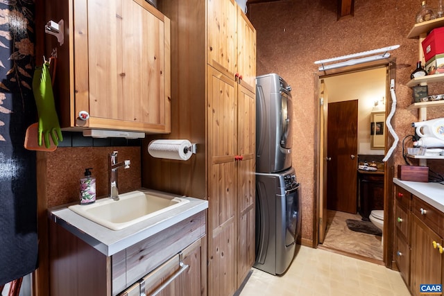 clothes washing area with sink and stacked washer / drying machine