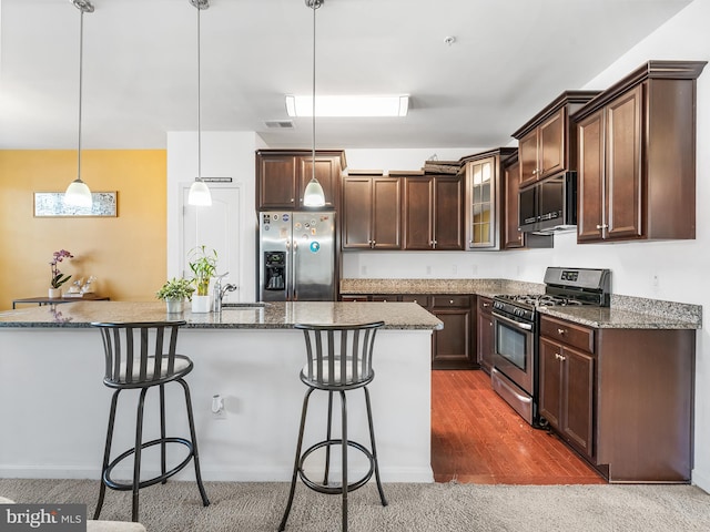 kitchen featuring appliances with stainless steel finishes, dark hardwood / wood-style floors, a kitchen island with sink, and hanging light fixtures