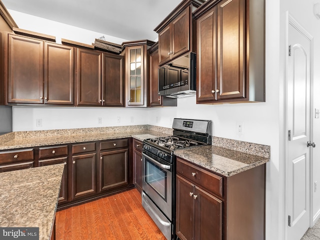 kitchen featuring appliances with stainless steel finishes, dark hardwood / wood-style floors, light stone counters, and dark brown cabinets