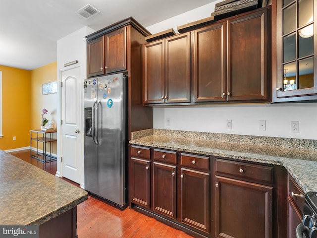 kitchen featuring stainless steel fridge, light stone counters, wood-type flooring, and range