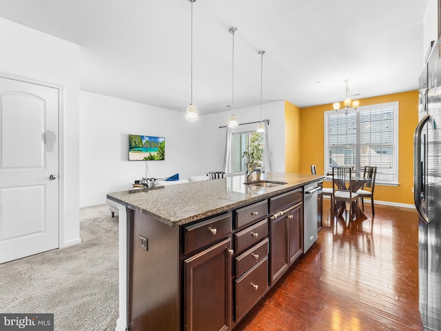 kitchen featuring a healthy amount of sunlight, a center island with sink, and hanging light fixtures