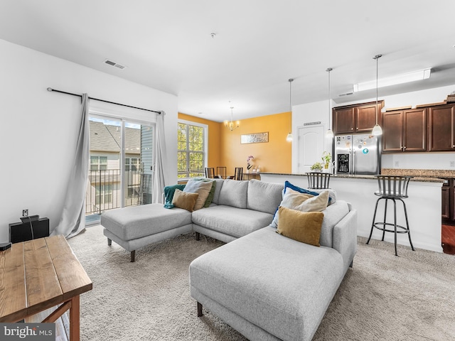 carpeted living room featuring a notable chandelier