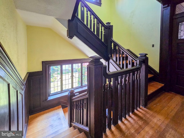 staircase featuring a textured ceiling, vaulted ceiling, and hardwood / wood-style flooring