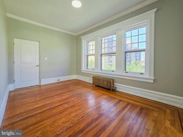 unfurnished room with hardwood / wood-style flooring, ornamental molding, radiator heating unit, and a wealth of natural light