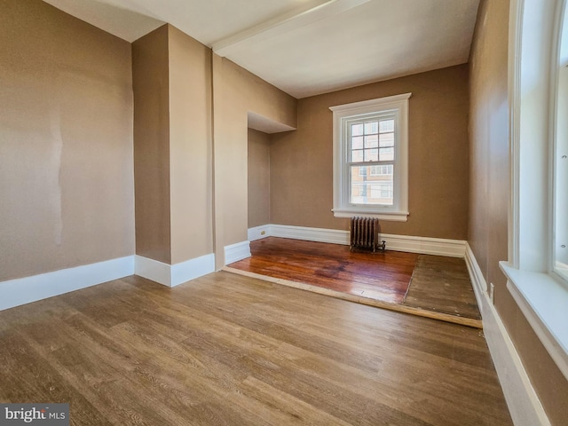 empty room featuring hardwood / wood-style flooring and radiator heating unit