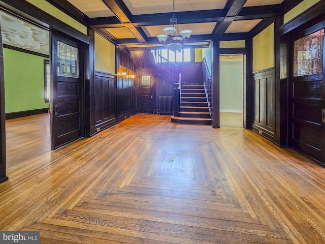 foyer with radiator, coffered ceiling, beamed ceiling, and a chandelier