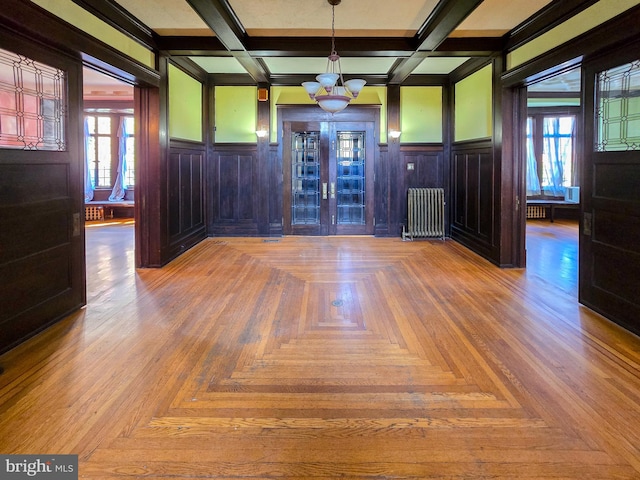 foyer entrance with beam ceiling, radiator, and plenty of natural light