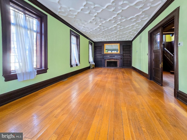 unfurnished living room featuring ornamental molding, a healthy amount of sunlight, and light wood-type flooring