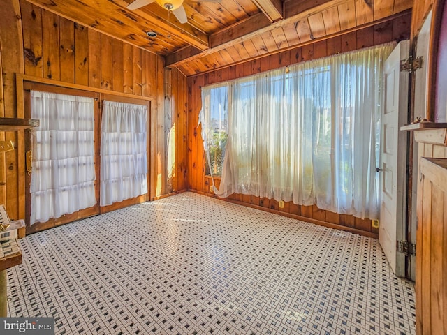 interior space featuring beamed ceiling, wooden walls, wooden ceiling, and ceiling fan