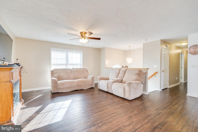 living room with a textured ceiling, ceiling fan, and dark hardwood / wood-style floors