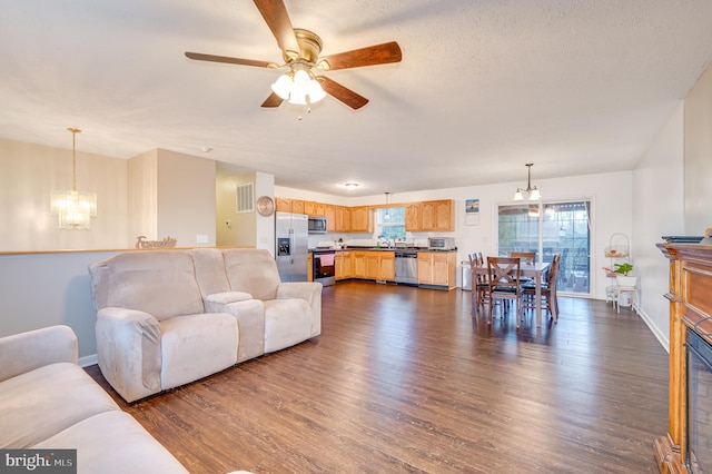 living room featuring a textured ceiling, ceiling fan with notable chandelier, dark hardwood / wood-style floors, and sink