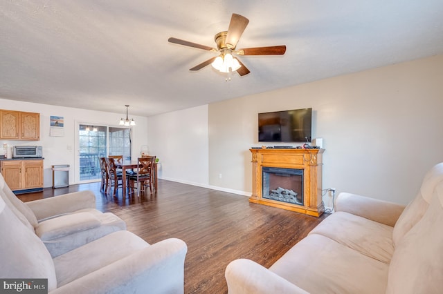 living room with ceiling fan with notable chandelier and dark hardwood / wood-style flooring