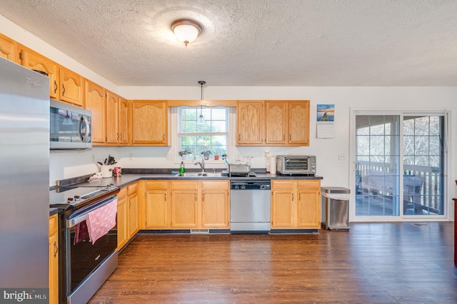 kitchen with appliances with stainless steel finishes, a textured ceiling, sink, pendant lighting, and dark hardwood / wood-style floors