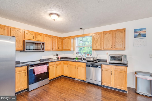 kitchen with dark hardwood / wood-style flooring, a textured ceiling, stainless steel appliances, sink, and decorative light fixtures