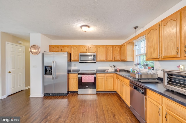 kitchen featuring pendant lighting, sink, dark hardwood / wood-style floors, a textured ceiling, and appliances with stainless steel finishes