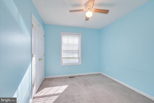 carpeted spare room with ceiling fan