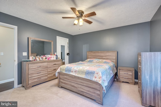 carpeted bedroom featuring ceiling fan and a textured ceiling