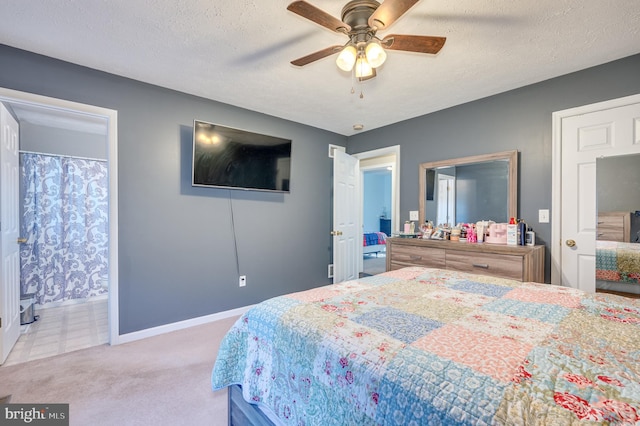 carpeted bedroom with a textured ceiling, connected bathroom, and ceiling fan