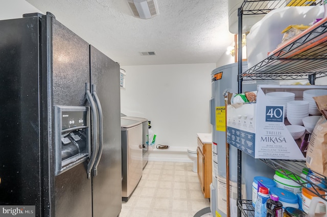 kitchen featuring black fridge with ice dispenser, a textured ceiling, washer and clothes dryer, and water heater