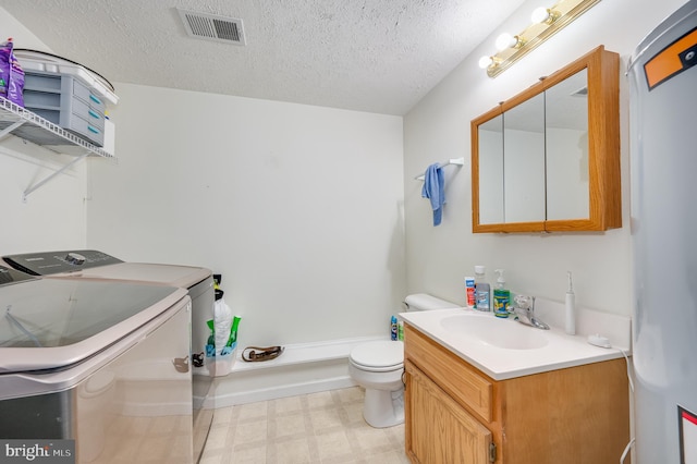 bathroom with vanity, independent washer and dryer, a textured ceiling, and toilet